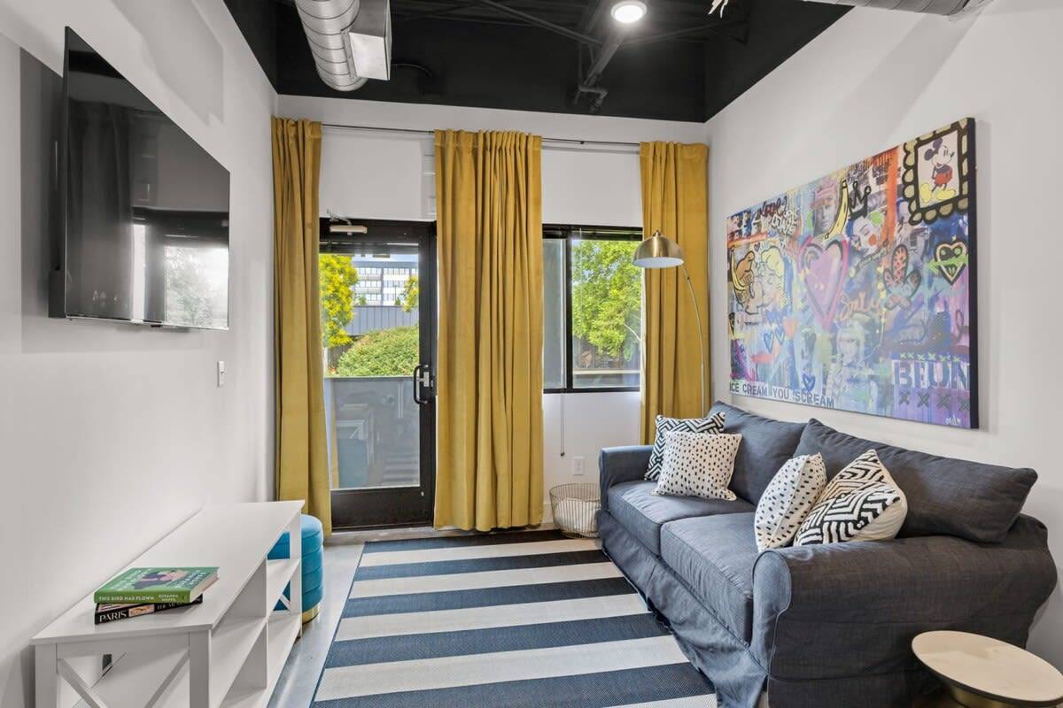 Welcome to a living room that seamlessly combines contemporary design with a touch of playfulness. The yellow striped rug adds a cheerful element to the space, complementing the sleek lines of the TV.