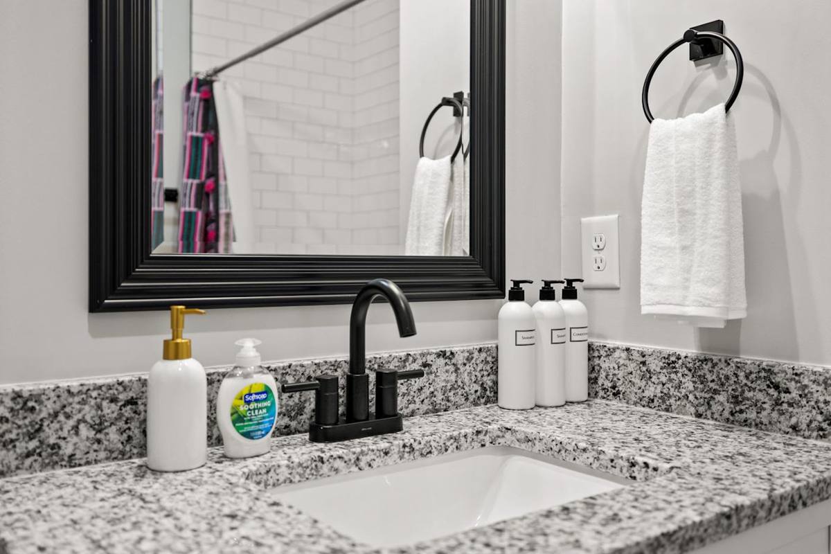Elevate your morning routine with the refinement of this contemporary bathroom, showcasing lavish granite countertops and a stylish black mirror that adds a touch of sophistication to your daily rituals.