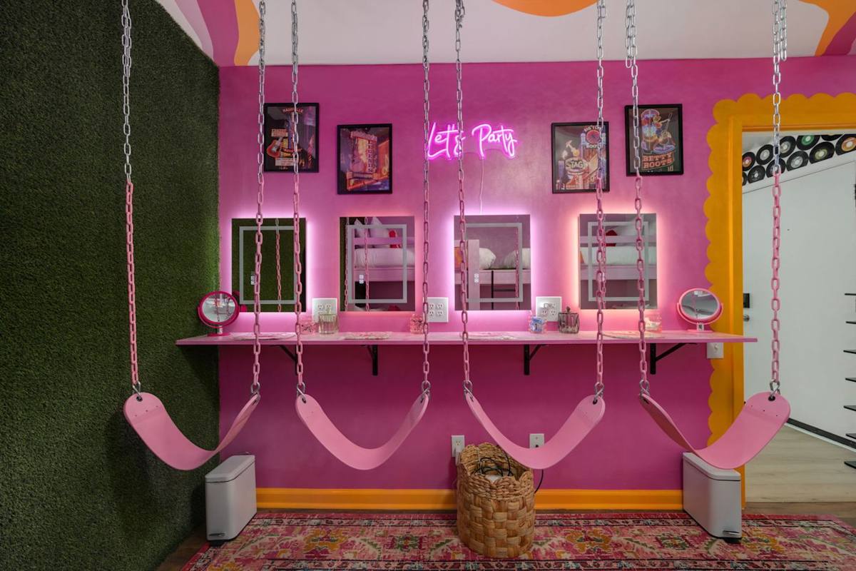 Vibrant room with swings, neon lights, and whimsical decor—perfect for fun selfies!