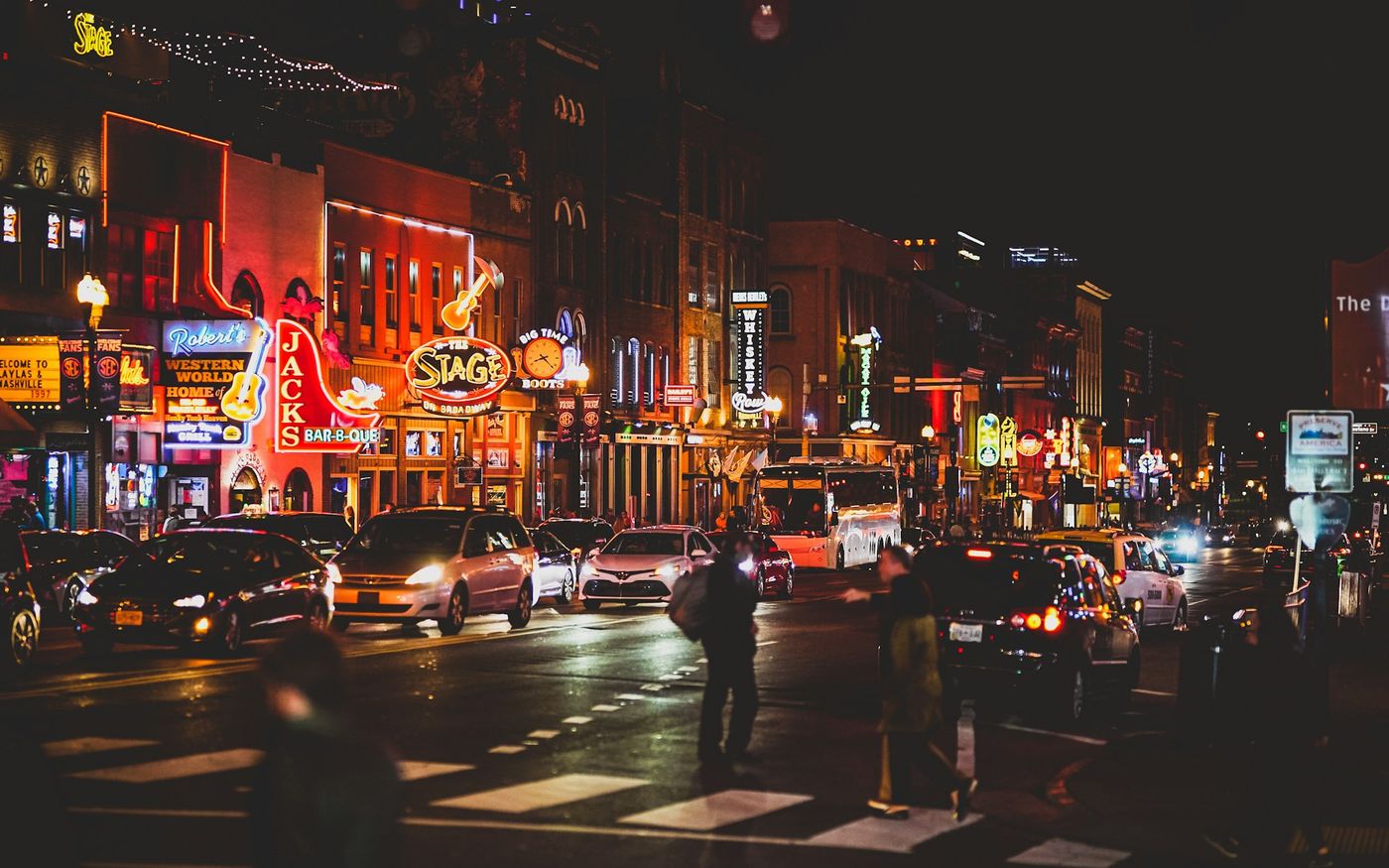 Lower Broadway at night, the crowd crossing under the neon honky-tonk signs
